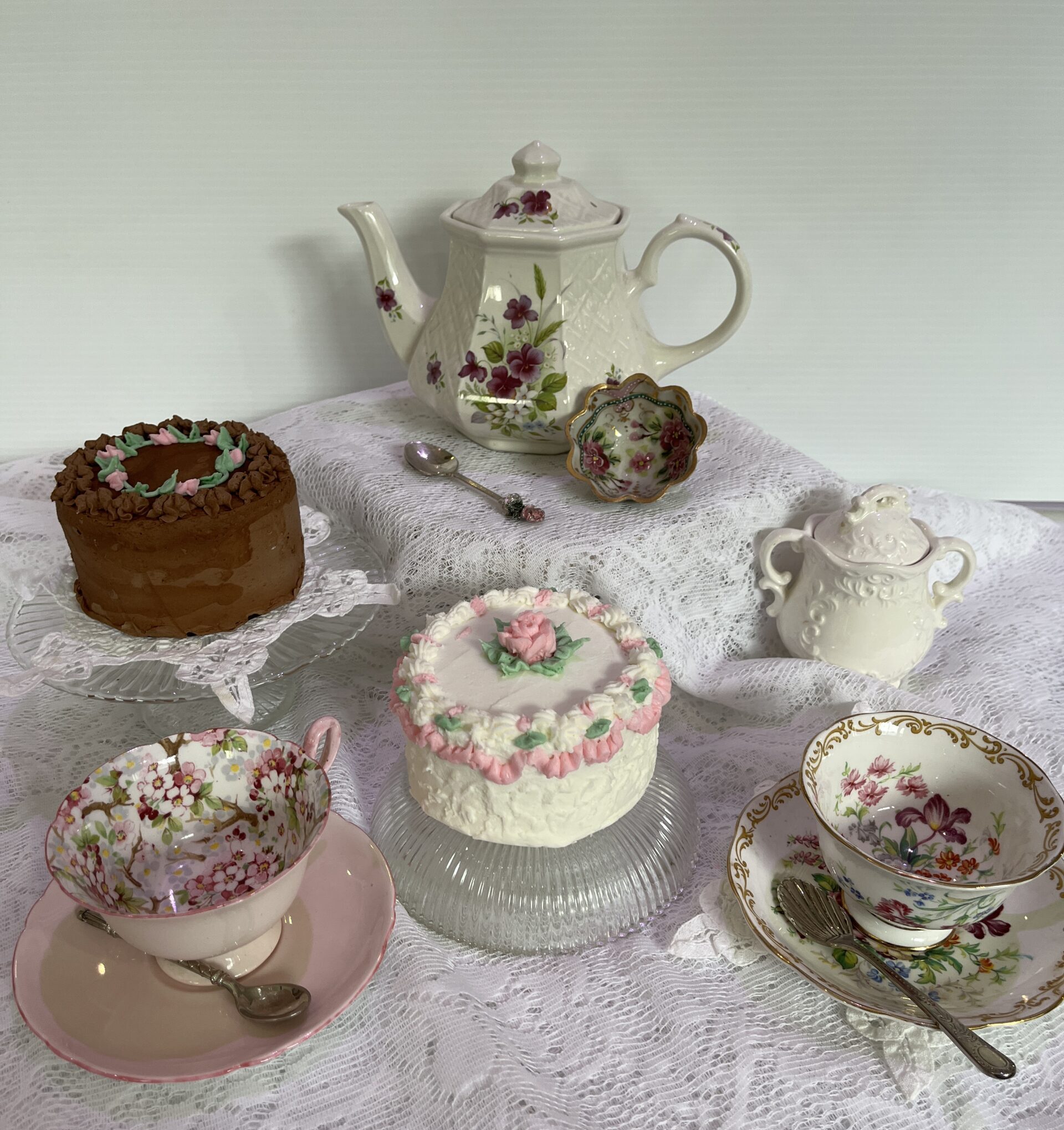 A table with several cakes and tea pots on it.