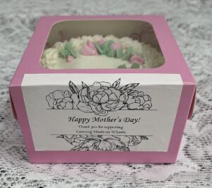 A pink box with a white and green cake inside of it.